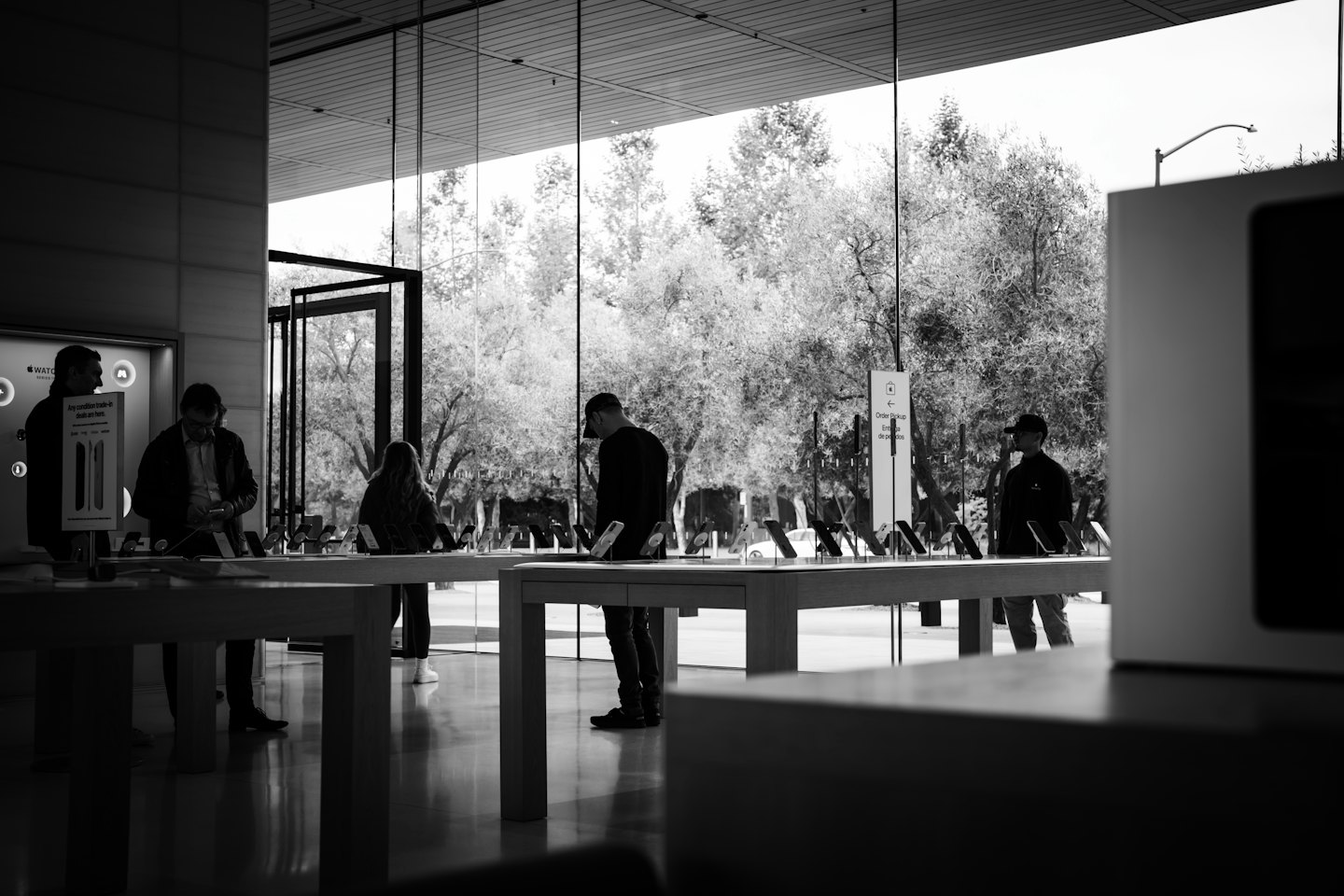 Customers examining electronics on tables in a bright store.